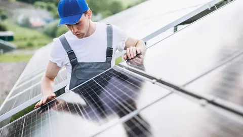 Un operario coloca placas solares en un tejado