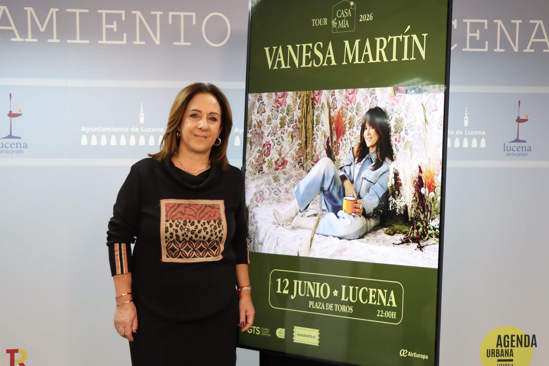 La concejal de Fiestas del Ayto de Lucena, Araceli Rodríguez, junto al cartel de presentación del concierto